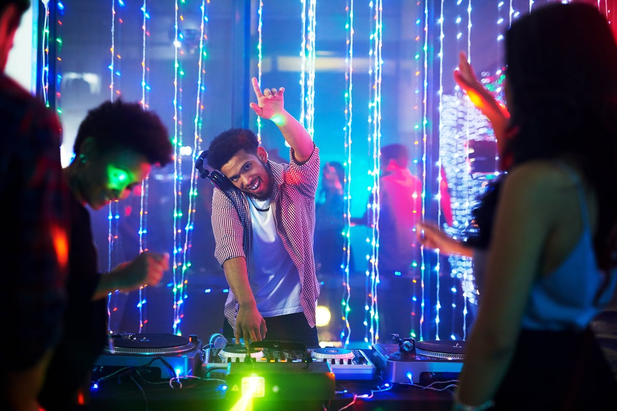 DJ musician man playing and mixing a song with a turntable and headphone. Dance party. excited dj sound device operator with headphones by dancing at club. concept of entertainment in  nightlife.